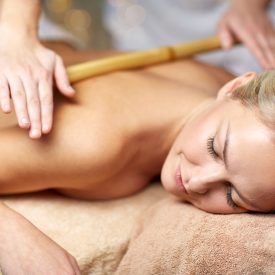 people, beauty, spa, healthy lifestyle and relaxation concept - close up of beautiful young woman lying with closed eyes and having bamboo massage in spa